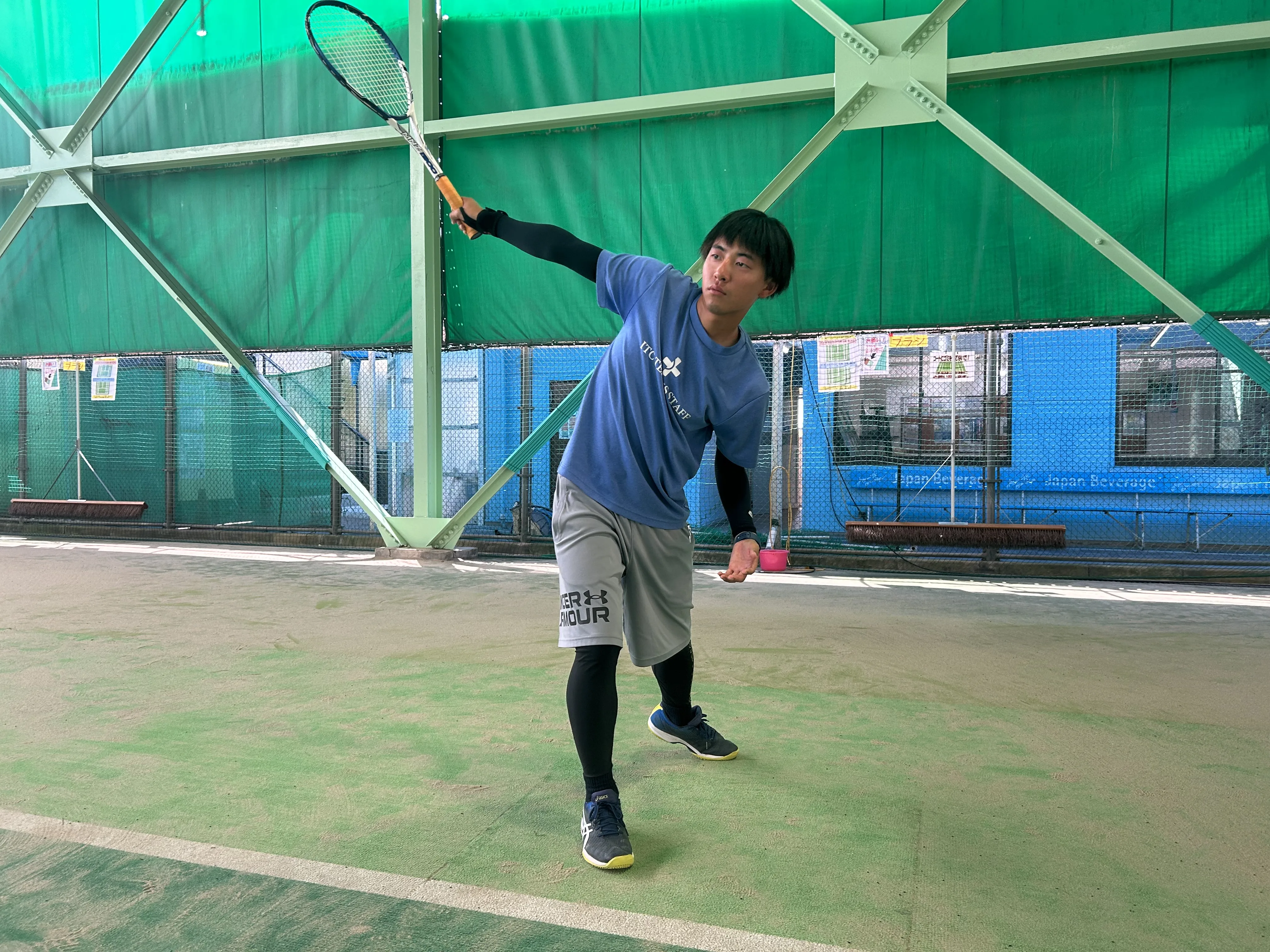 ソフトテニスのレシーブでバックハンドストロークを打っている男性