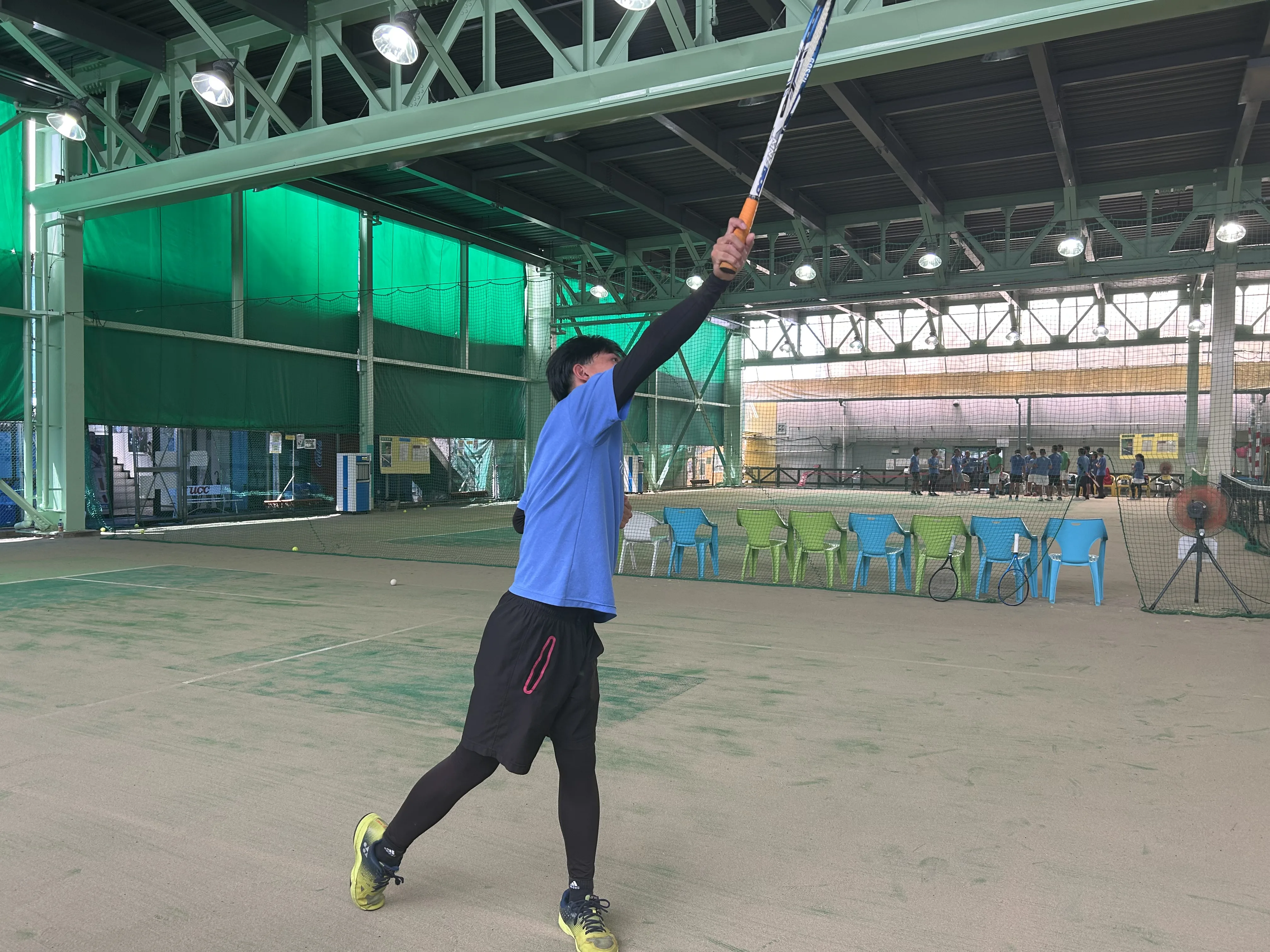 ソフトテニスのスマッシュで打点を確認している男性