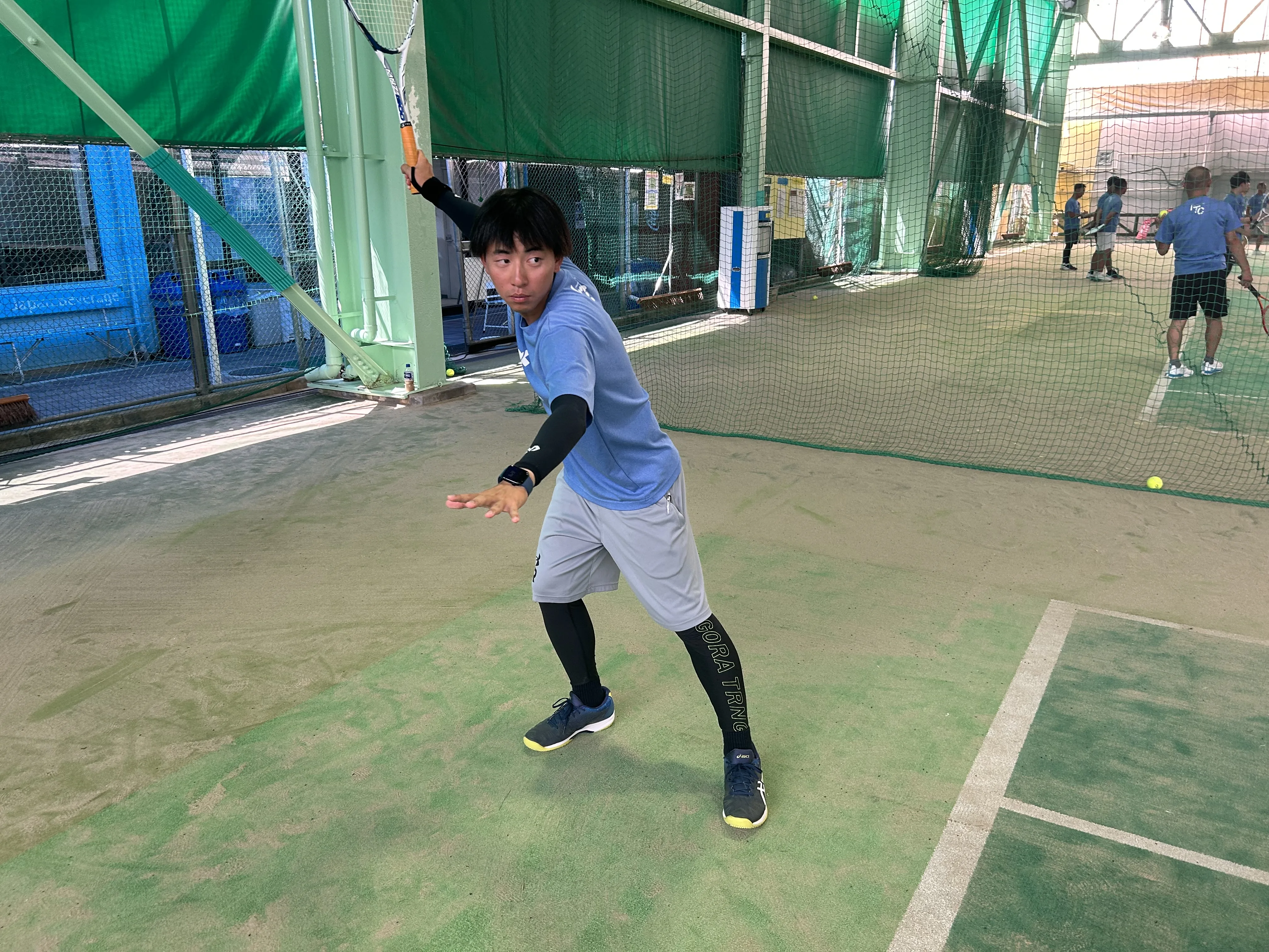 ソフトテニスのトップ打ちをしている男性
