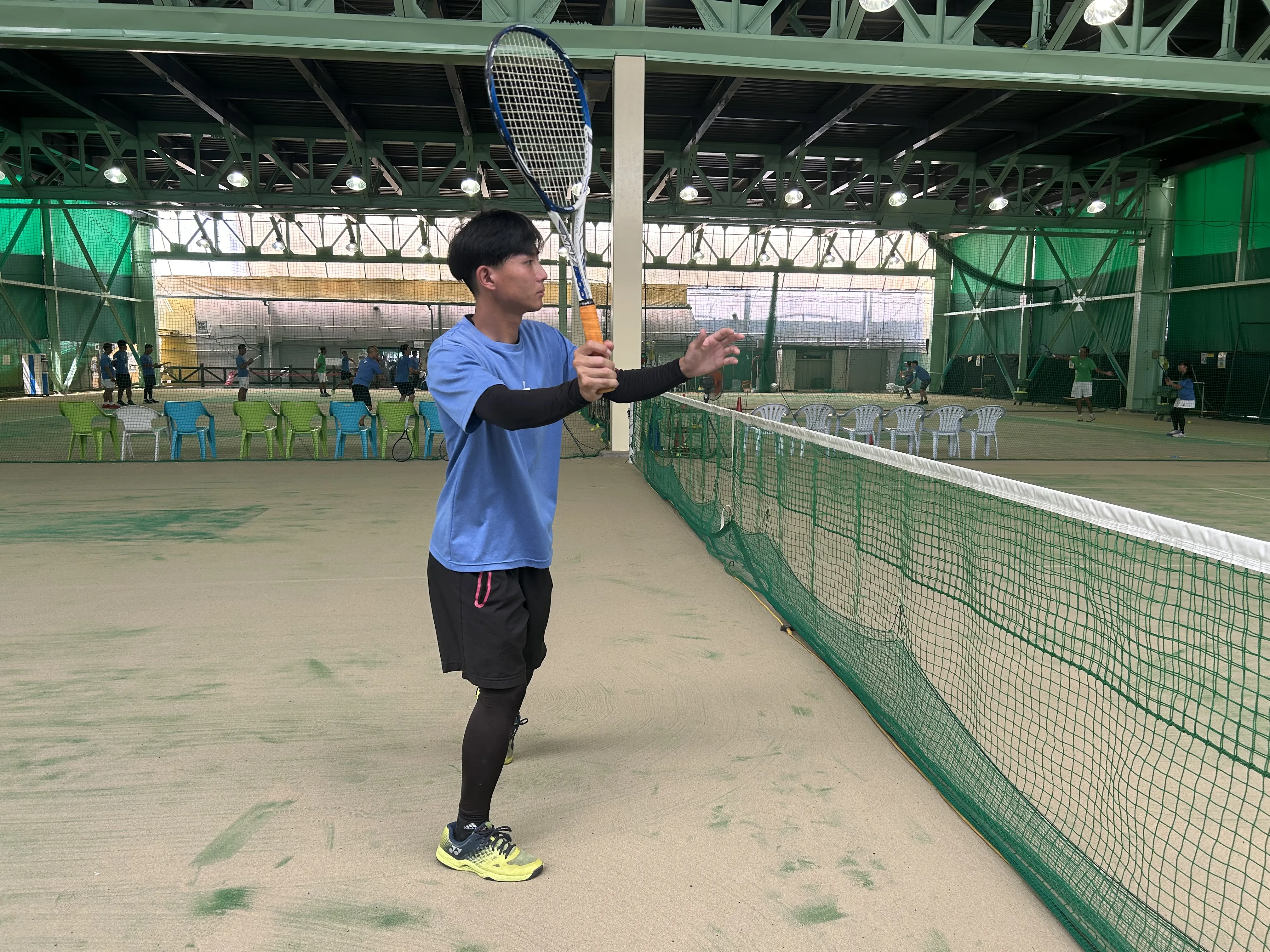 ソフトテニスのボレーをネット際で打っている男性