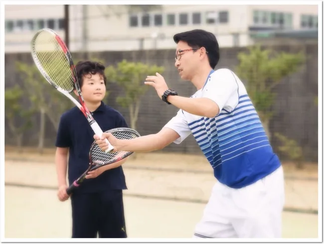 ソフトテニスのボレーを教えるコーチ